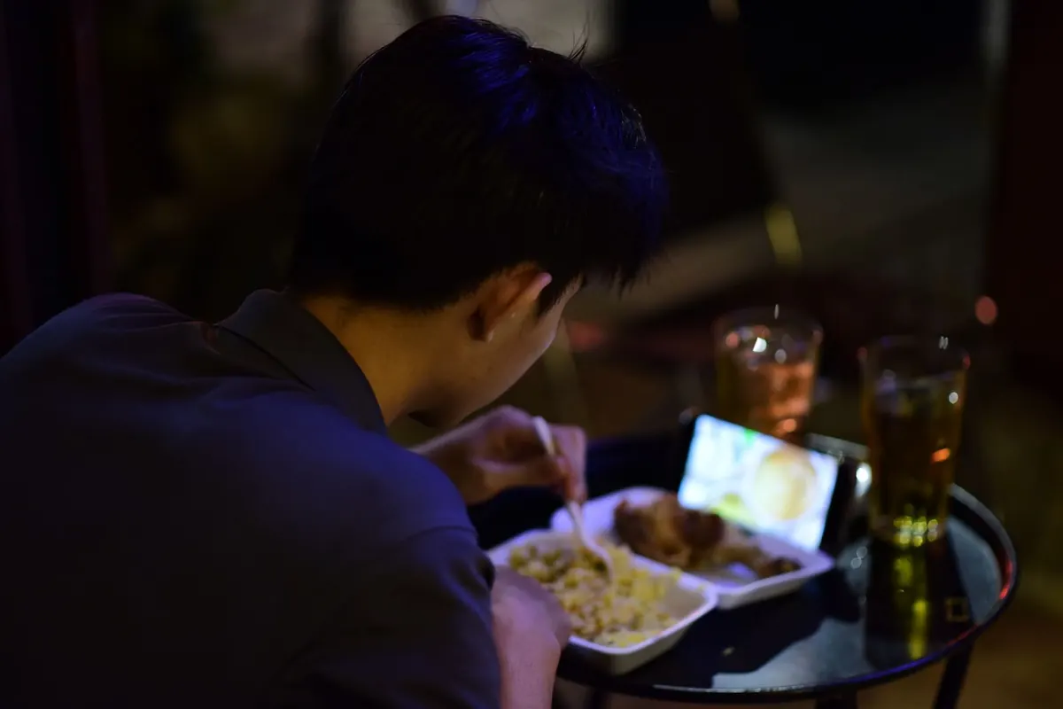 Someone eating a meal while watching a video on their phone.