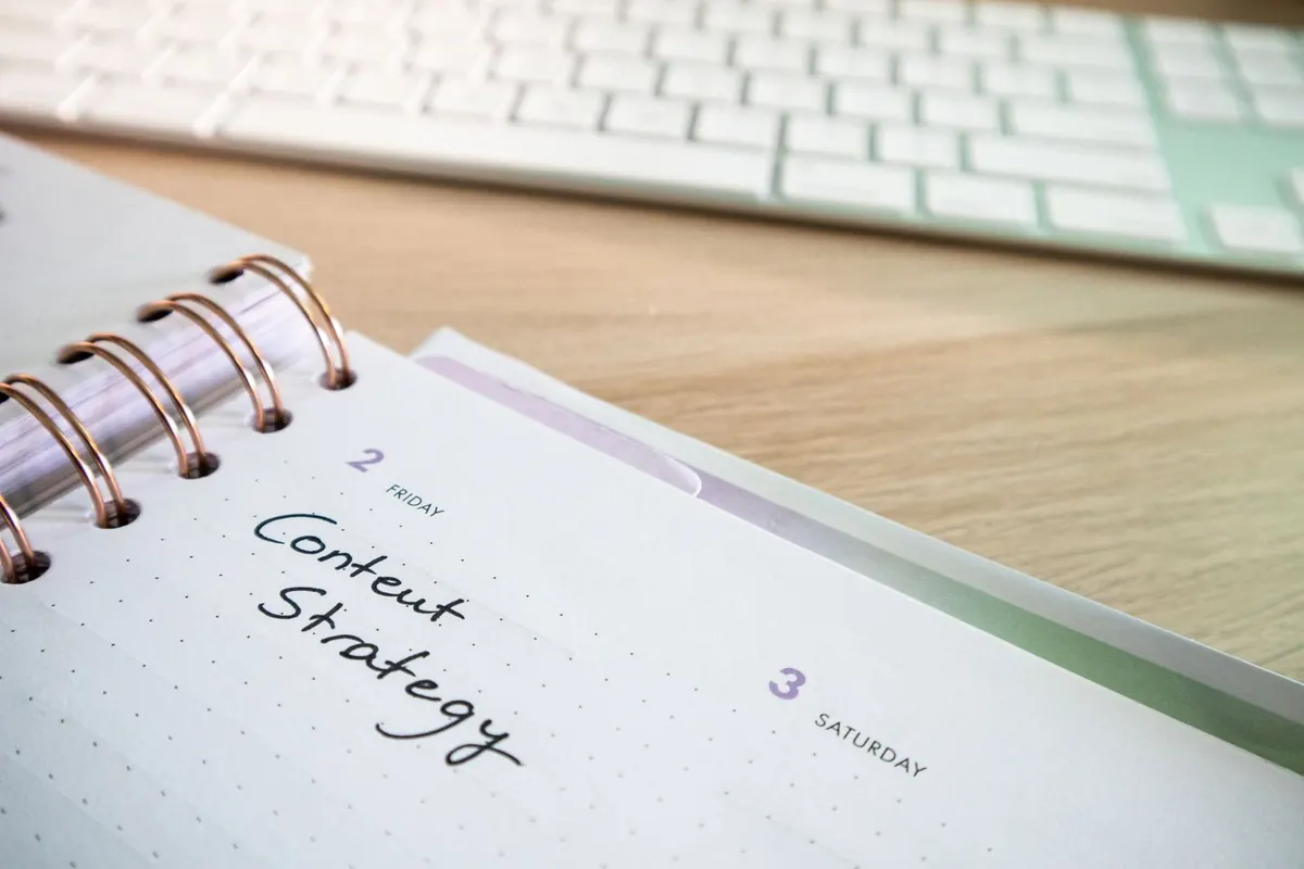 A paper planner on a desk with content notes written in it, beside a keyboard.