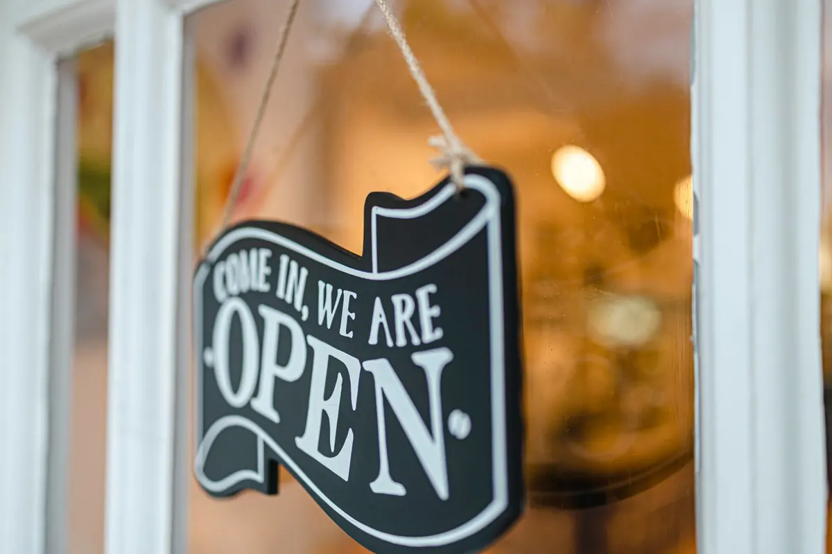 An open sign hanging in a shop window.