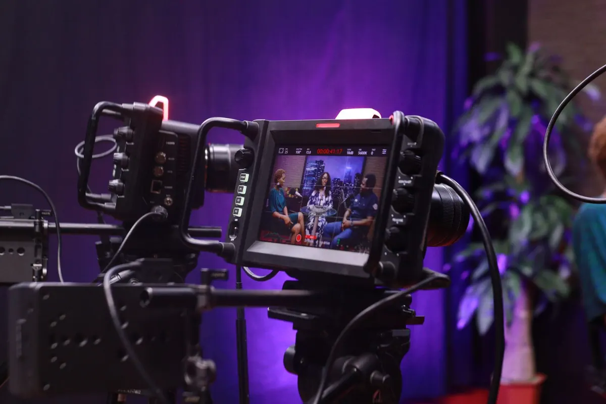 A camcorder on a tripod, set up in front of an interview scene.