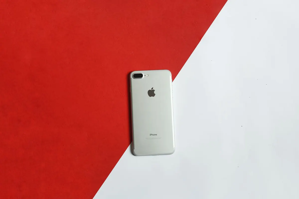 A silver smartphone lying on a red and white background, photographed from directly above.
